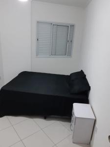 - un canapé noir dans une chambre blanche avec fenêtre dans l'établissement Apartamento 2 dorm na Guilhermina com tudo novo, Localização Incrível! Internet 200 MB, à Praia Grande