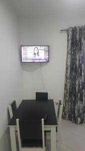 a dining room with a table and a tv on the wall at Apartamento 2 dorm na Guilhermina com tudo novo, Localização Incrível! Internet 200 MB in Praia Grande