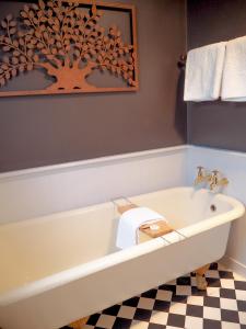 y baño con bañera y una pared con una foto de árbol. en The Gables B&B, en Picton