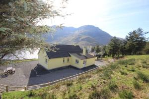 a small yellow house with a mountain in the background at Lough Fee Renvyle in Renvyle +21 photos