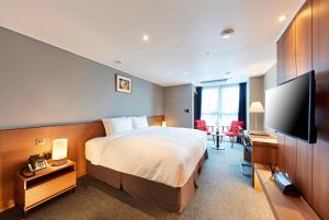 a hotel room with a bed and a flat screen tv at Ramada by Wyndham Gumi in Gumi