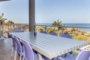 a long table and chairs on a balcony with the ocean at Danara Place in Zinkwazi Beach