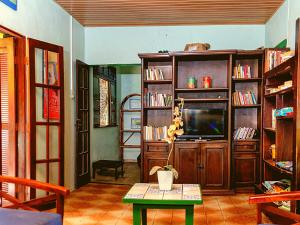 a living room with a tv and book shelves at Villas Boas in Arraial do Cabo