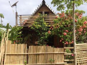 une maison en bois derrière une clôture ornée de fleurs dans l'établissement The Village House, à Puerto Princesa