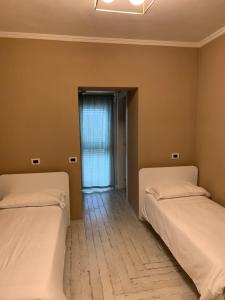 two beds sitting in a room with a window at Locanda il Deserto in Livorno