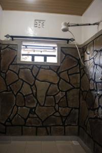 a bathroom with a stone wall and a window at Reens Vacation Rentals in Nakuru +23 photos