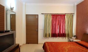Schlafzimmer mit einem Bett, einem TV und einem Fenster in der Unterkunft Nu Delhi Homestay in Neu-Delhi