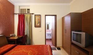 a hotel room with a bed and a television and a table at Nu Delhi Homestay in New Delhi