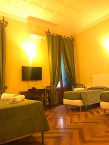 a room with two beds and a tv on the wall at Hotel Giglio in Florence
