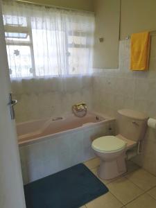 a bathroom with a toilet and a tub and a sink at 1102 High Tide Amanzimtoti in Amanzimtoti