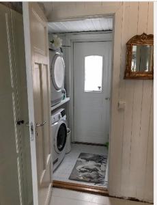 a laundry room with a washing machine and a door at Småbruket stall solheim in Rødby