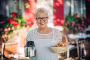 an older woman holding a basket of bread at Landgasthof Keller in Überlingen