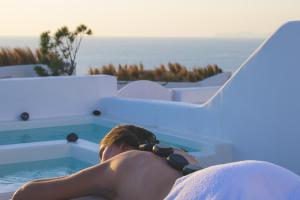 a man laying on a chair next to a swimming pool at Santolia Art Suites in Oia
