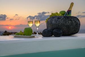 a table with two glasses of champagne and a bowl of fruit at Santolia Art Suites in Oia