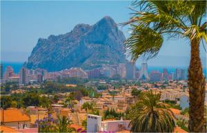 een berg op de achtergrond van een stad met palmbomen bij Home SEA&DREAMS NiceView in Calpe