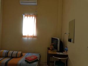 a bedroom with a bed and a desk with a window at Hotel Musafir Inn in Padang