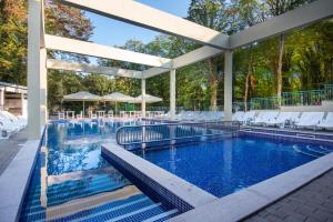 a swimming pool with white chairs and a swimming poolvisor at Ariana Hotel in Kiten