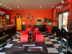 un restaurant avec des murs rouges, une table et des chaises rouges dans l'établissement hôtel Le Cosy, à Pont-de-Chéruy