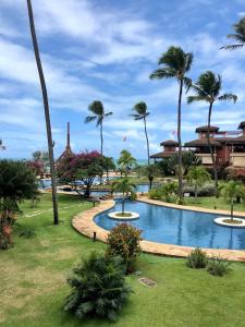 a resort swimming pool with palm trees in the background at Beach front apartment in Dream Village Cumbuco, Ceara in Cumbuco