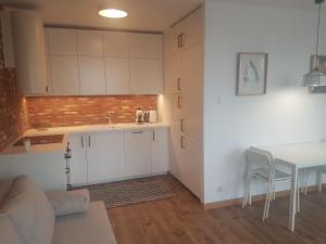 una cocina con armarios blancos y una mesa en una habitación en Apartament Młynarska - indywidualny dostęp, en Piaseczno