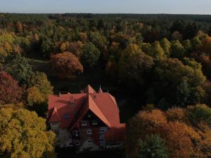a house with a red roof in the middle of a forest at Pałac Myśliwski Orle in Mirosławiec