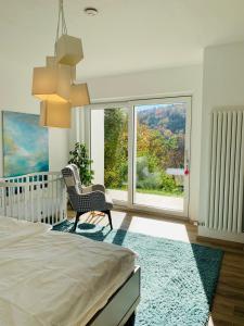 a bedroom with a crib and a chair and a large window at Apartment Am Kupferhammer in Pforzheim