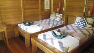 two twin beds in a room with wooden walls at Two Fish Resort Bunaken in Bunaken