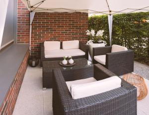 eine Terrasse mit Korbstühlen und einem Sonnenschirm in der Unterkunft Vitality Relax Spa Suite in Kloten