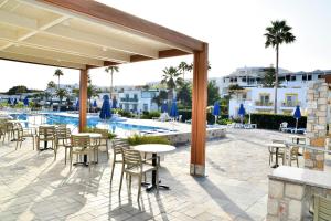 a patio with tables and chairs next to a pool at Mastichari Bay Hotel in Mastihari