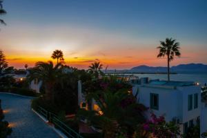 a sunset over a city with palm trees and a building at Mastichari Bay Hotel in Mastihari