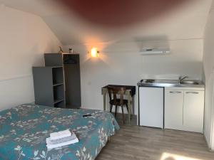 um pequeno quarto com uma cama e uma cozinha em hôtel Le Cosy em Pont-de-Chéruy