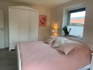 1 dormitorio con 1 cama grande con sábanas y almohadas rosas en Ferienwohnung Gartenstadt, en Flensburg