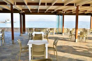 a restaurant with tables and chairs and the ocean at Mastichari Bay Hotel in Mastihari