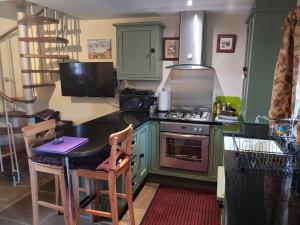 a kitchen with green cabinets and a stove and a table at Pellcroft Cottage in Holmfirth