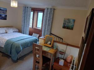 a bedroom with a bed and a desk with a mirror at Pellcroft Cottage in Holmfirth