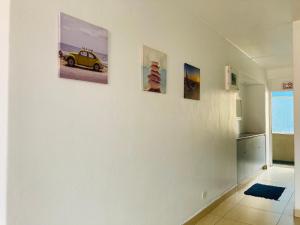 a room with three paintings of a car on a wall at 605 Tenbury Beach Apartment in Durban