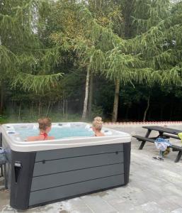 Dos personas sentadas en un jacuzzi en un patio trasero en Emda Country living close to Legoland en Billund