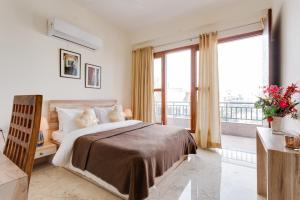 een slaapkamer met een groot bed en een balkon bij Hostie Eva Dreams - Private 2 BHK Apartments near Artemis, Medanta, Fortis hospitals in Gurgaon