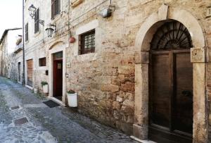 ein altes Steingebäude mit einer Holztür auf einer Straße in der Unterkunft Cantina Dell'Arte in Ascoli Piceno