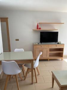 
a living room with a table and chairs and a tv at Apartamentos Oasis Maspalomas in Maspalomas
