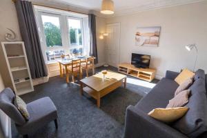 ein Wohnzimmer mit einem Sofa und einem Tisch in der Unterkunft ☆ Bright, 2 Bedroom West End Apartment ☆ in Dundee
