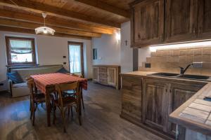 una cocina con armarios de madera y una mesa con sillas. en Chalet Mountain Relax - CIR 0001, en Rhêmes-Notre-Dame
