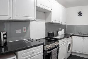 uma cozinha com armários brancos e um forno com placa de fogão em ☆Modern Flat, Close to University and City Centre☆ em Dundee