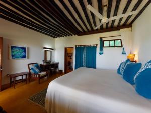 a bedroom with a white bed and a desk at Peponi Hotel Lamu - Kenya in Shela