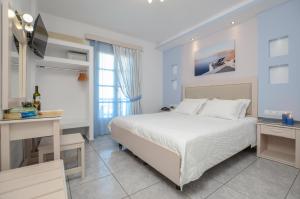 a white bedroom with a bed and a desk at Ilion Hotel in Naxos Chora