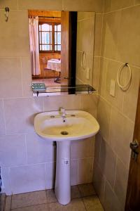 een badkamer met een witte wastafel en een spiegel bij FRIDA in Puerto Iguazú