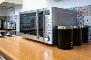 a microwave oven sitting on top of a wooden counter at ☆Bright Apartment, Near University + City Centre☆ in Dundee