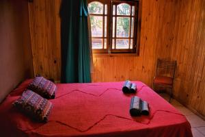 um quarto com uma cama vermelha e uma janela em FRIDA em Puerto Iguazú