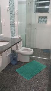 ein Badezimmer mit einem WC und einer Dusche mit einer grünen Matte in der Unterkunft Apartamento 3 quartos de cobertura na Praia Grande em Ubatuba in Ubatuba