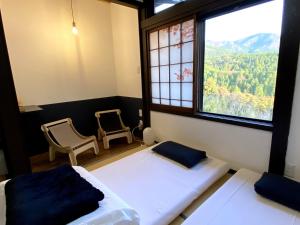 a bedroom with two beds and a large window at Guesthouse Nedoko in Nakatsugawa